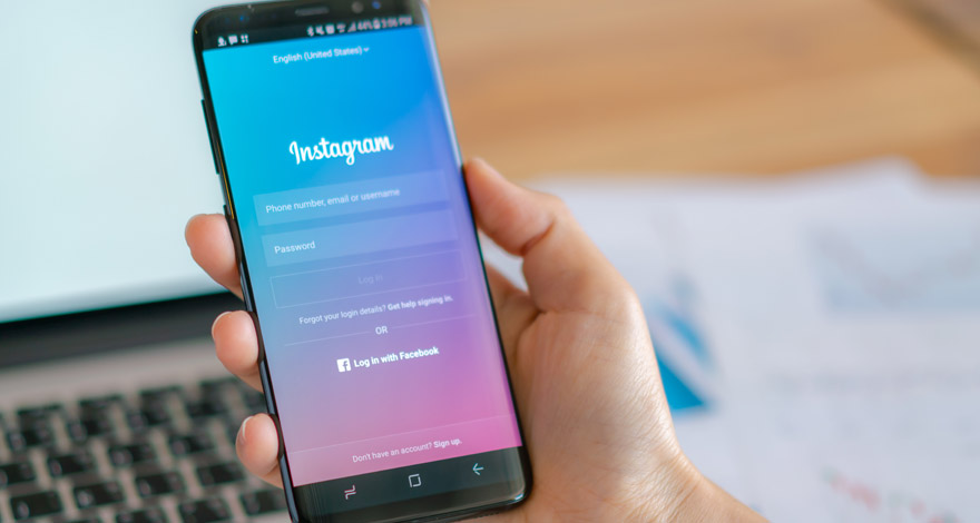 Una manos sosteniendo un móvil, en su pantalla aparece la página de inicio de Instagram Shopping